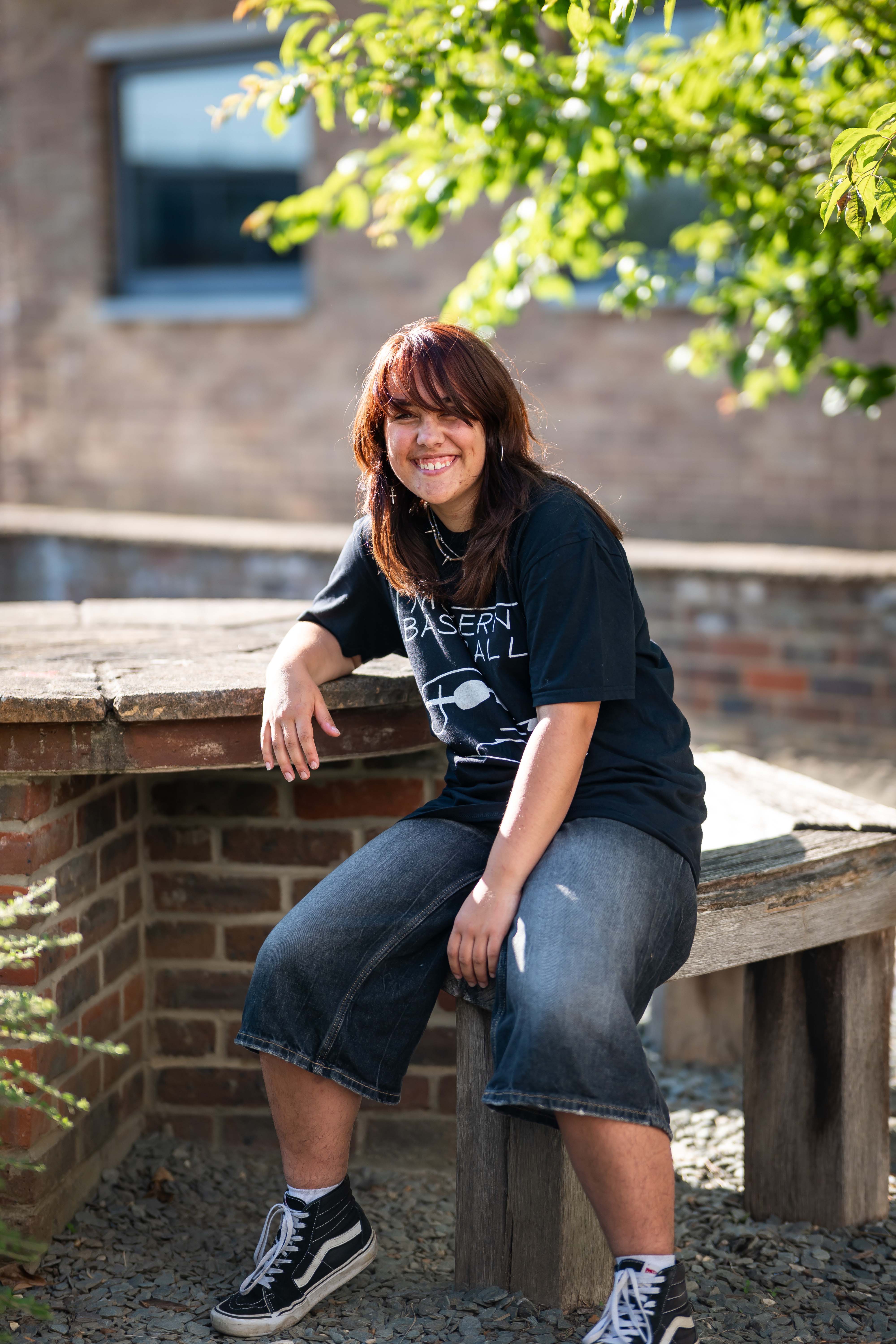 Student sat smiling on bench
