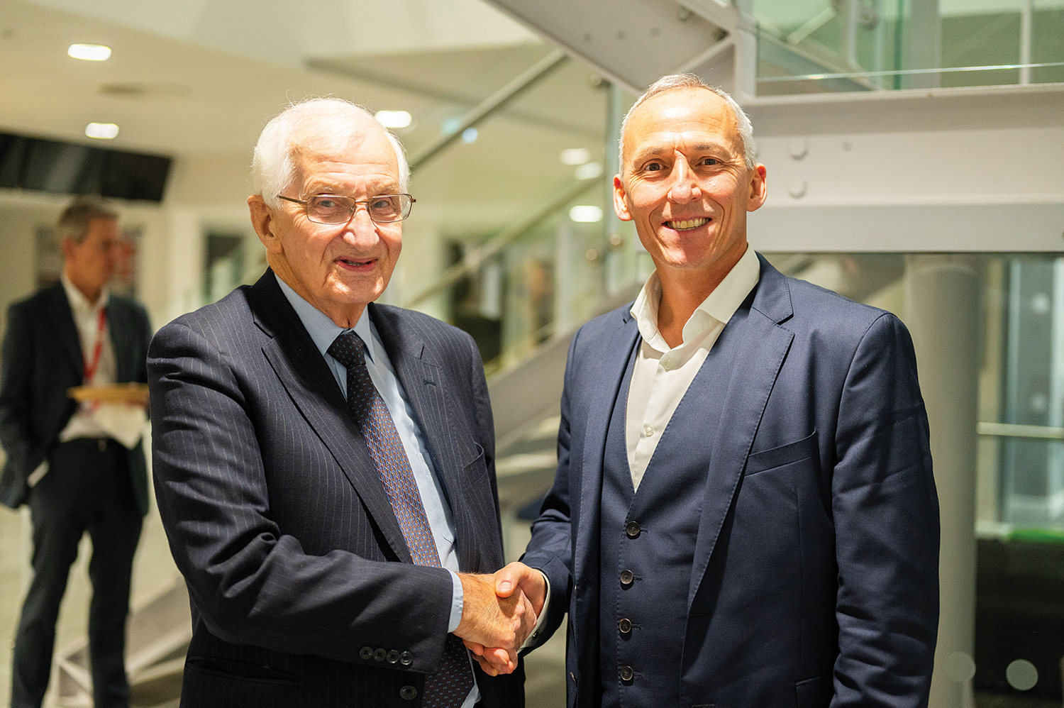 Two men shaking hands, wearing suits