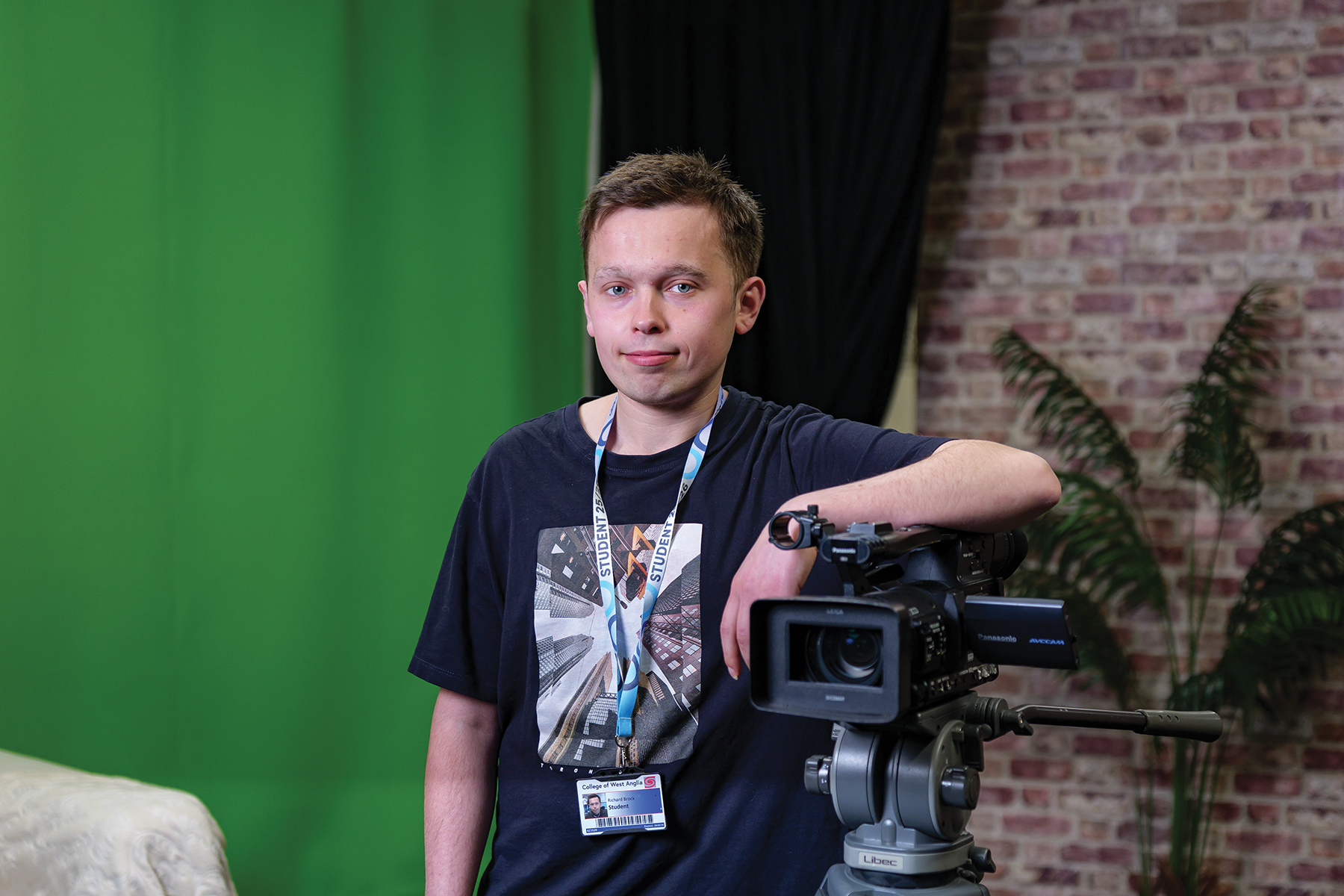 student leaning against camera in green screen studio